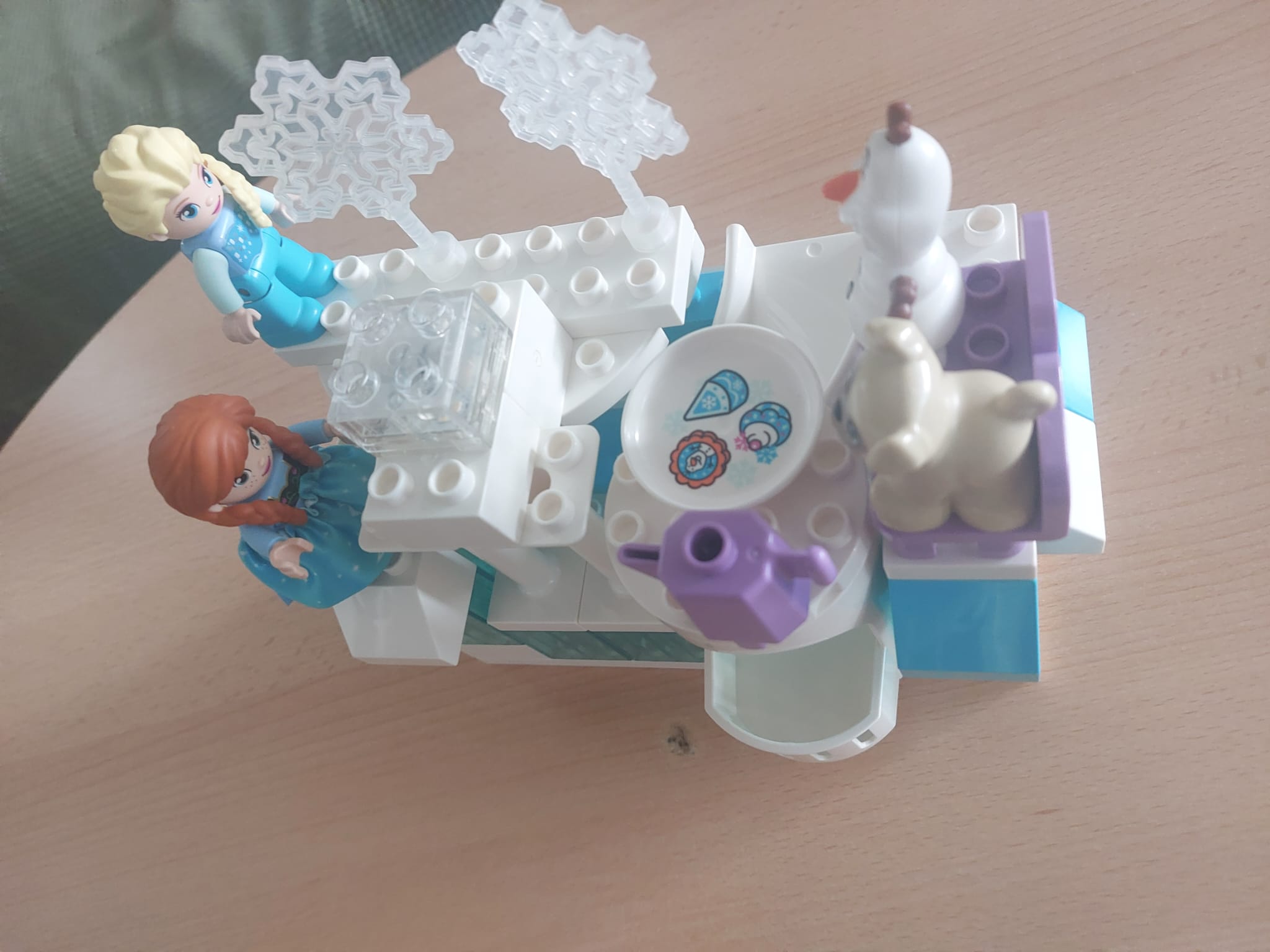 spezialgebietsfremdes Kunstwerk aus Lego Duplo Steinen und Figuren mit Hund und Schneemann an der Kaffeetafel